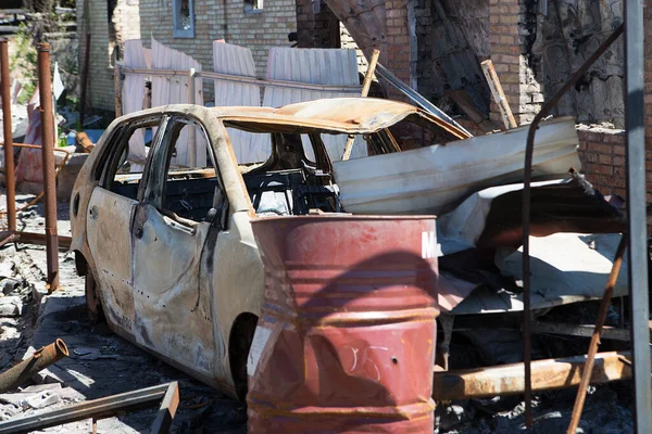 Bucha, Kyiv bölgesi - 5 Mayıs 2022: Şehrin bombalanmasından sonra yanan araba yıkılmış bir evin avlusunda duruyor. Rusya ile Ukrayna arasındaki savaş, 5 Mayıs 2022.