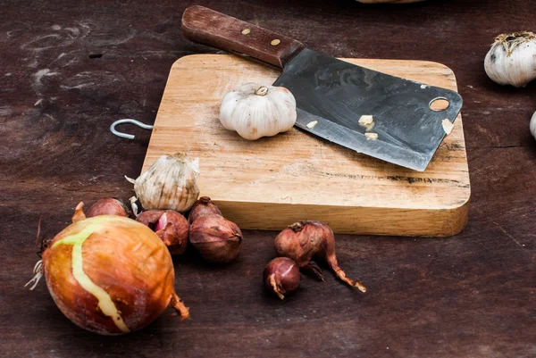 Chalotas, cebola, alho, tábua de corte e faca — Fotografia de Stock