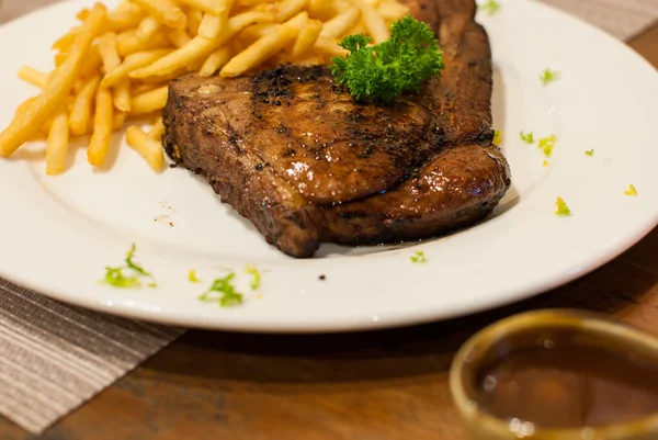 Vepřová kotleta na grilu steak s hranolky, top s petrželkou. — Stock fotografie