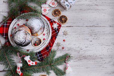 Yeni yılın planı bu. Çikolatalı çörekler ve pudra şekeri, yeni yıl dekoru, nar taneleri, hafif ahşap arka planda köknar dalları. Üst görünüm, alanı kopyala.