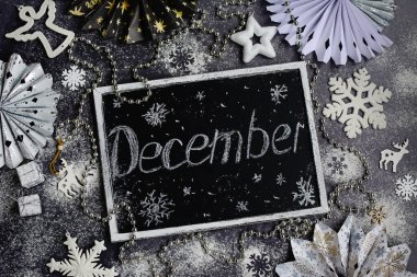 Beyaz kar taneleri ve el yazması yazması Aralık. Siyah karatahtaya yazı yazılmış. Yeni yıl ve Noel konsepti.
