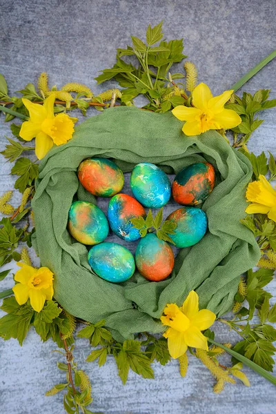 Composizione verticale. Uova di Pasqua multicolori in un nido decorativo su uno sfondo blu. Vista dall'alto — Foto Stock