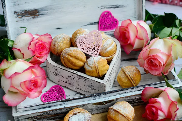 Gros plan de délicieux biscuits dans une boîte décorative en forme de cœur et un bouquet de roses sur un fond de lumière douce. — Photo