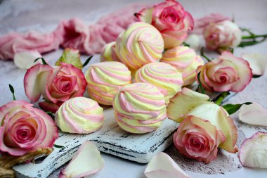 Gri arka planda çok renkli marşmelov ve güller. Güzel tatil konsepti