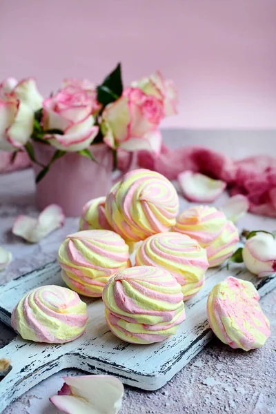 Composizione verticale. Un bouquet di rose e un delizioso marshmallow rosa-giallo su sfondo grigio — Foto Stock