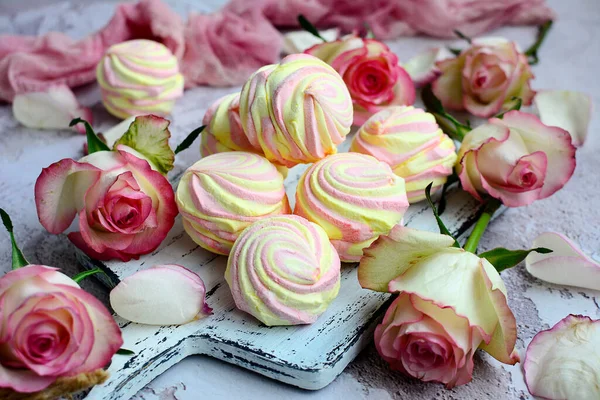 Vackert semesterarrangemang. Rosor och läckra färgade marshmallows på en grå bakgrund — Stockfoto