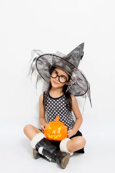Mała czarownica myślenia z dyni w strój halloween — Zdjęcie stockowe