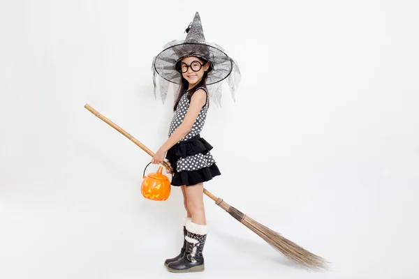 Asian witch child holding magic broom in Halloween dress — Stock Photo, Image