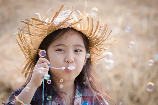 Glückliches asiatisches Kind spielt Blase mit Strohstapel — Stockfoto