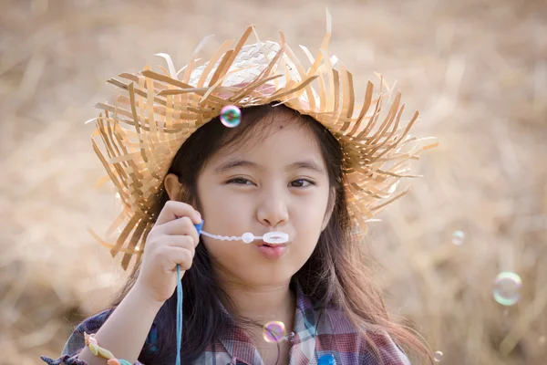 Glückliches asiatisches Kind spielt Blase mit Strohstapel — Stockfoto