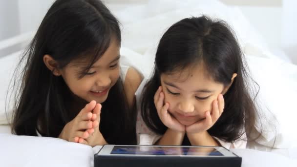 Pequeñas chicas asiáticas jugar tableta en la cama — Vídeo de stock