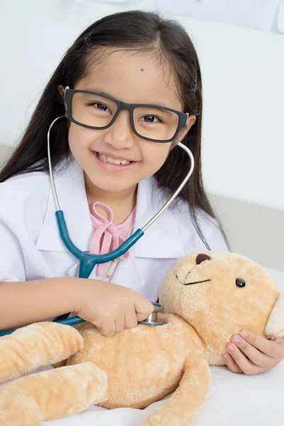 Asian girl playing as a doctor with stethoscope and bear doll — Stock Photo, Image