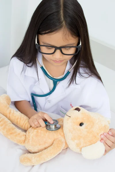Azjatyckie dziewczyny gry jako lekarz z lalka stetoskop i niedźwiedzia — Zdjęcie stockowe