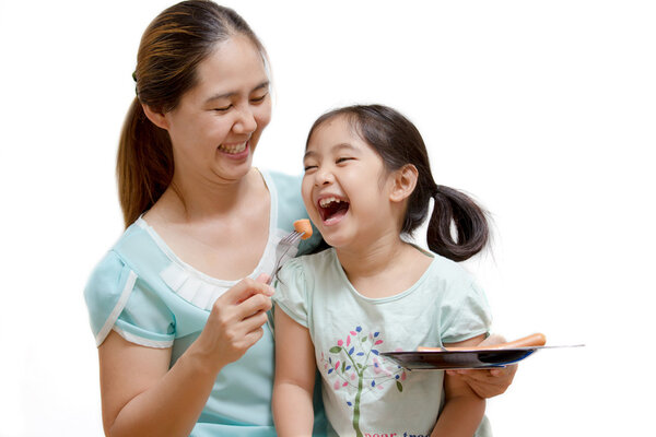 Asian mother feeding sausage to her daughter