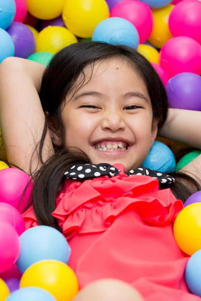 Criança asiática feliz brincando no jardim de infância com bolas coloridas — Fotografia de Stock