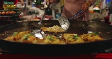 Chef using giant pan fried clams, delicious street food in Thailand.