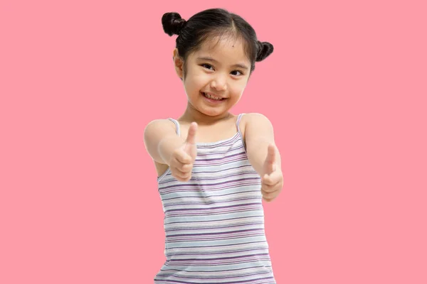 亚洲美丽而自信的小女孩的画像 她的大拇指在粉色背景下显得孤立无援 — 图库照片