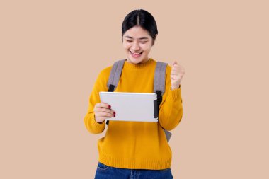 Asyalı genç kız izole edilmiş arka planda tablet bilgisayar kullanıyor.