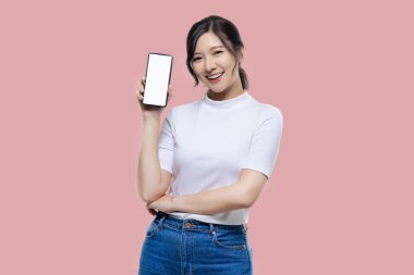 Happy young Asian woman feeling happiness and gesture showing mobile smartphone blank screen on isolated pink background.