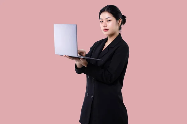 Young modern business asian woman holding laptop computer isolated over pink background.