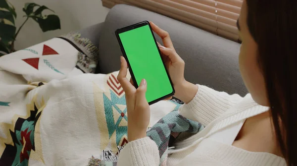 Junge Asiatin Mit Smartphone Auf Couch Mit Grünem Bildschirmschlüssel Stockbild