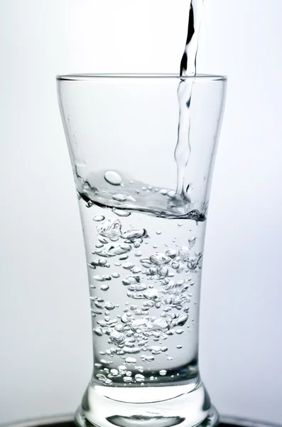Наповнення склянки водою, що показує концепцію напою — стокове фото