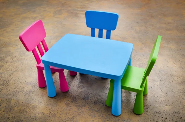 Table and three chairs on concrete floor