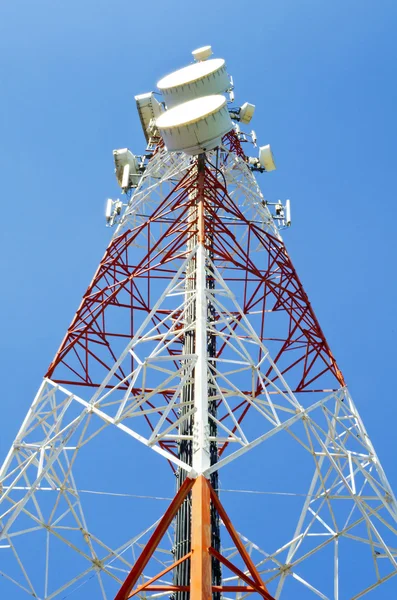 Komunikační věž s anténami proti modré obloze — Stock fotografie