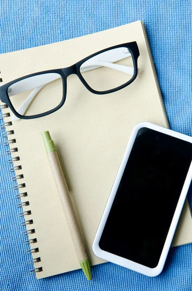 Office supplies Notebook paper smartphone and glasses — Stock Photo, Image