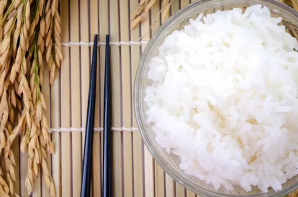 Bowl of white steamed rice with chopsticks on bamboo mat. — Stock Photo, Image