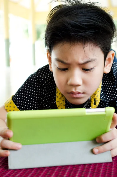 Weinig Aziatische jongen glimlacht met tablet pc op zijn gezicht — Stockfoto