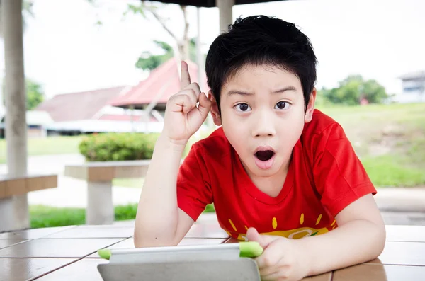 Pequeño chico asiático sonríe con tableta ordenador — Foto de Stock