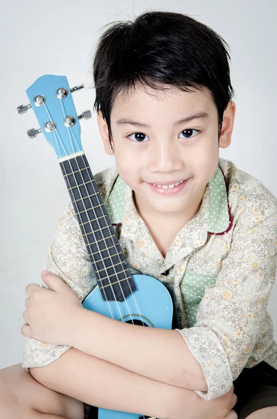 アジアの子供彼のウクレレ — ストック写真