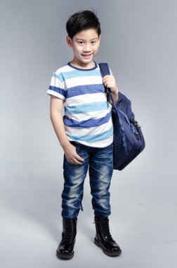 küçük Asyalı çocuk onun asılmış bir kit çanta ile ayakta gerekir