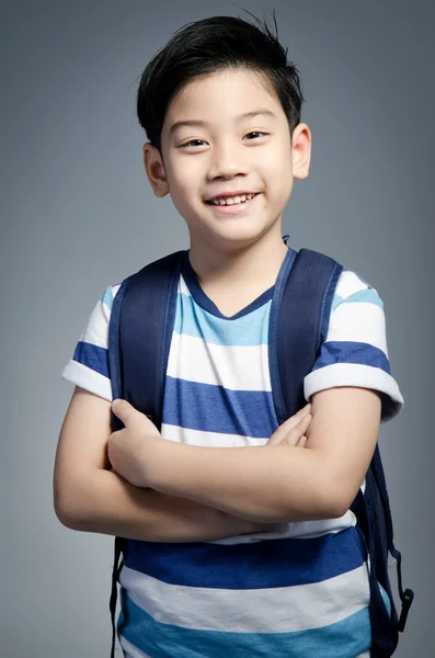 Little Asian child standing with a kit bag slung over his should — Stock Photo, Image