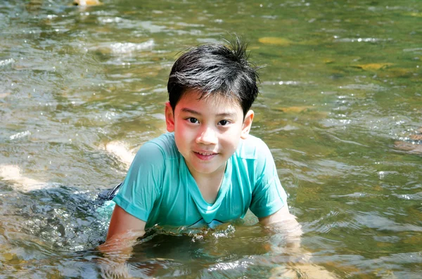 Joven lindo chico jugando en el agua en un hermoso río —  Fotos de Stock