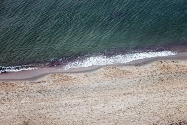 Arkaplan kumlu deniz kıyılarından ve dalgalardan oluşur.