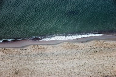 Arkaplan kumlu deniz kıyılarından ve dalgalardan oluşur.