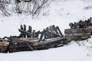 Kış mevsiminde ağaç gövdelerinden ve dallardan oluşan eski çökmüş ahşap çitler.