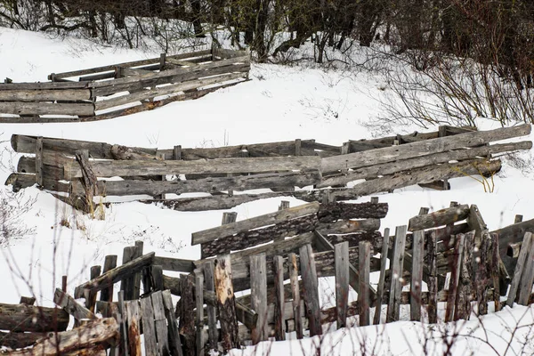 Kış mevsiminde ağaç gövdelerinden ve dallardan oluşan eski çökmüş ahşap çitler.