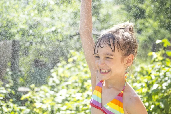 Niña en un spray de agua en verano — Foto de Stock
