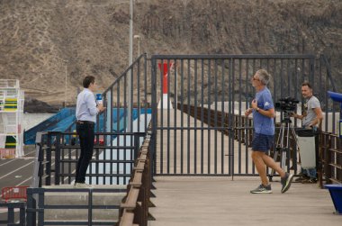 Sunucu ve TV kameramanı koşan bir adamın yanında..