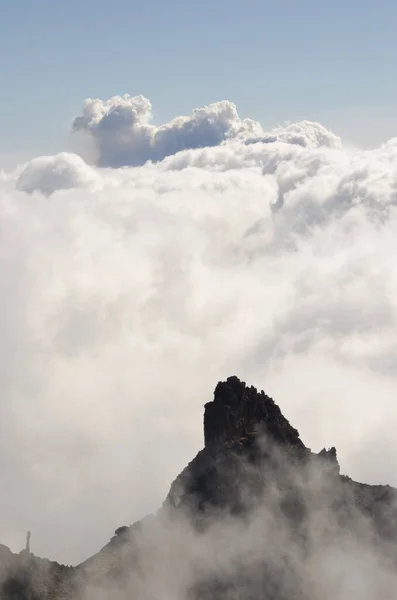 Acantilado, mar de nubes y columna de humo de una erupción volcánica. — Foto de Stock