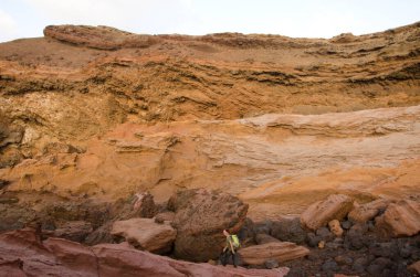 Büyük kayaların arasında bir uçurumun altında yürüyen kadın..