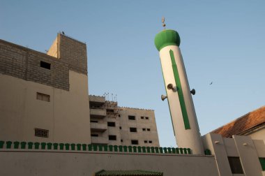 Bir caminin minaresi ve siyah uçurtmalar Milvus migrans bir binanın çatısına tünemişti. Dakar. Senegal.