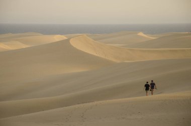 Two men walking in the Maspalomas Dunes. Natural Reserve of the Maspalomas Dunes. San Bartolome de Tirajana. Gran Canaria. Canary Islands. Spain.