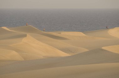 People in sand dunes. Special Natural Reserve of the Maspalomas Dunes. San Bartolome de Tirajana. Gran Canaria. Canary Islands. Spain.