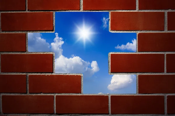 Cihlová zeď a modrou oblohu s mraky a slunce. — Stock fotografie