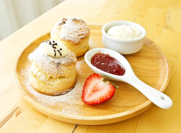 Scone spread with cream and strawberry jam — Stock Photo, Image