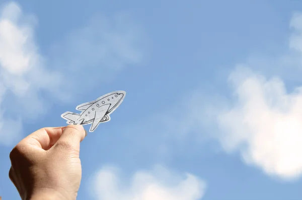 Mão segurando avião de papel em um fundo de céu — Fotografia de Stock